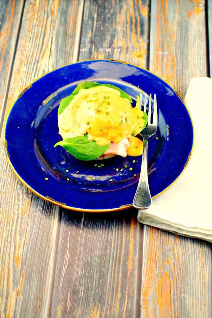 Eggs benedict on a blue plate with fork