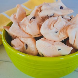 close up of chocolate chip meringue cookies in a green bowl