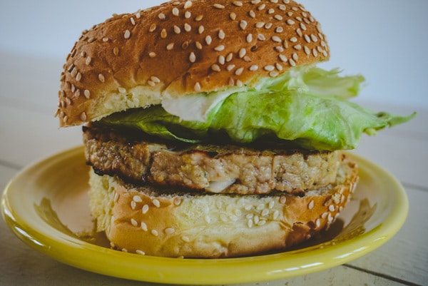close up of turkey burger on a yellow plate with bun and lettuce
