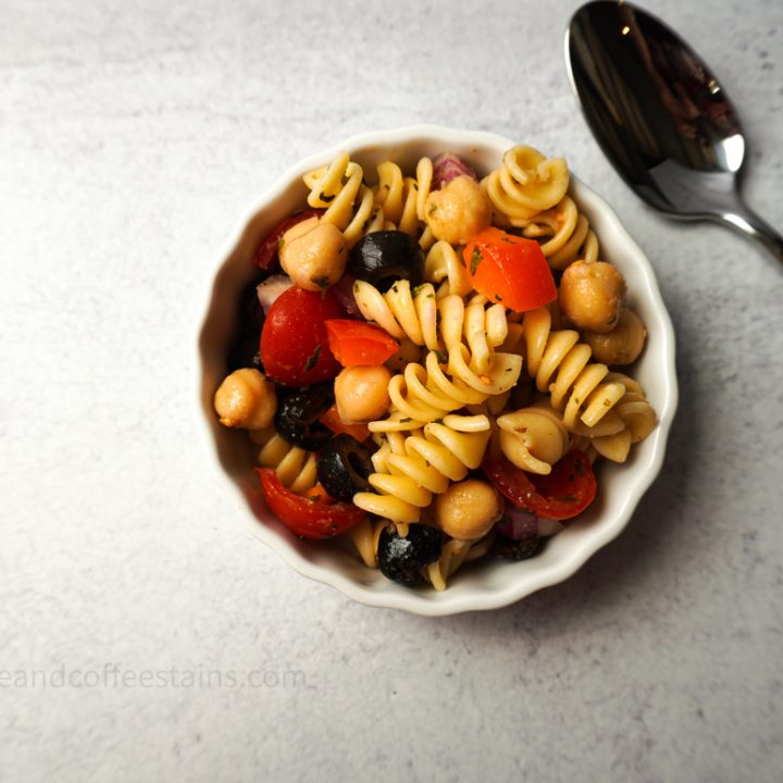 vegan pasta salad in a white bowl with spoon