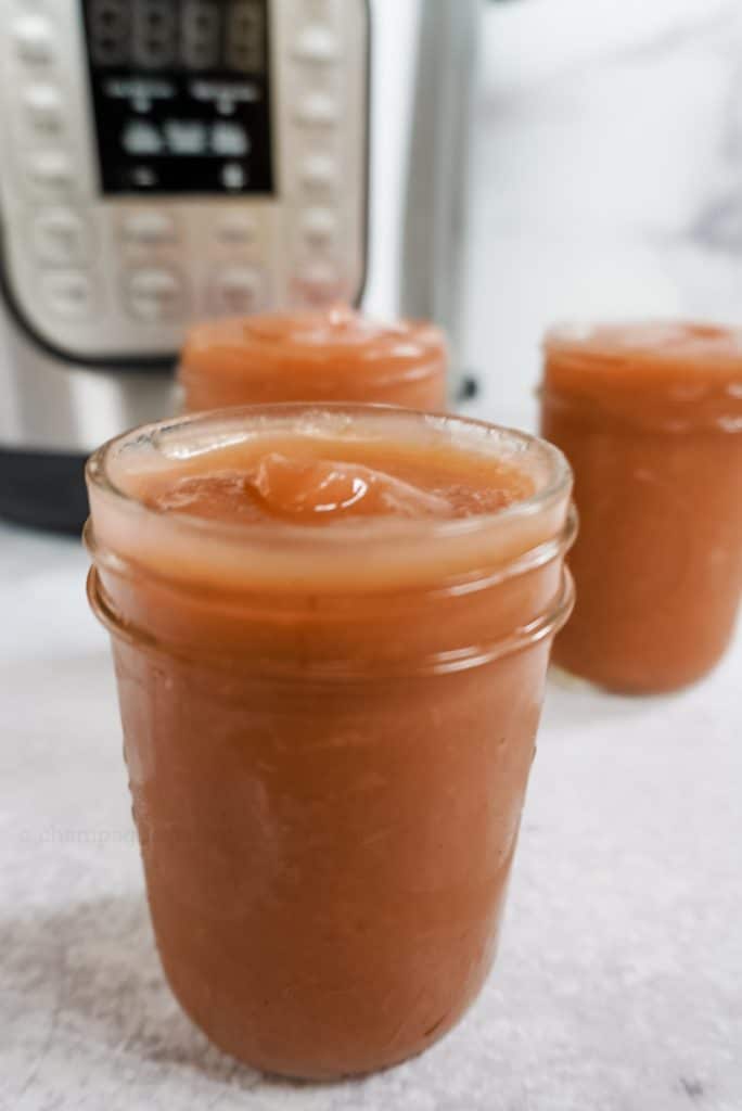 apple butter in a mason jar in front of an instant pot