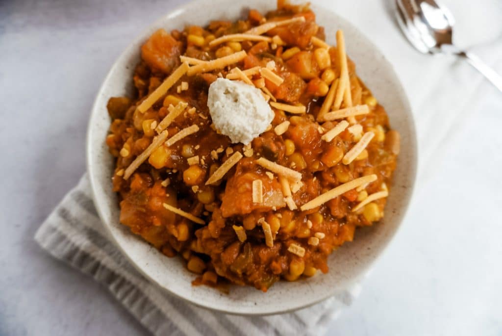 chili in a white bowl with cheese and vegan sour cream