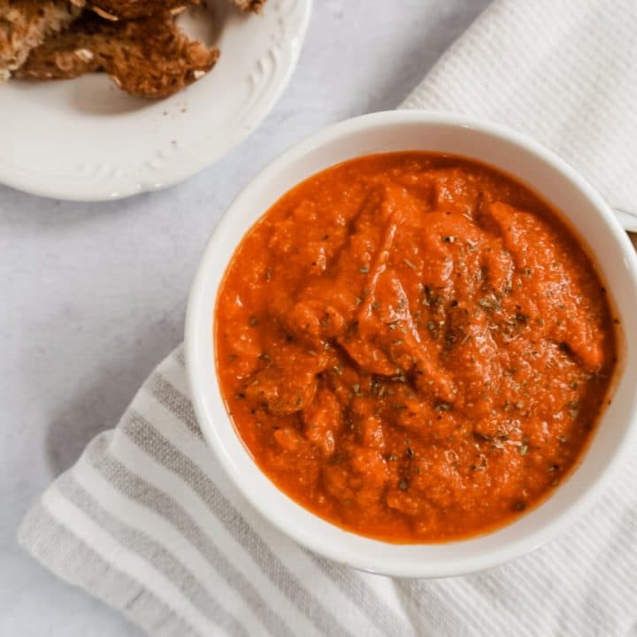 tomato basil soup in a white bowl with a napkin
