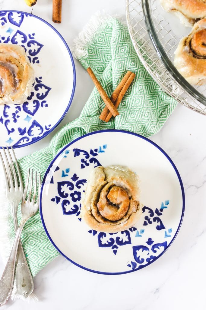 overhead of a cinnamon roll on a plate with 2 forks next to it