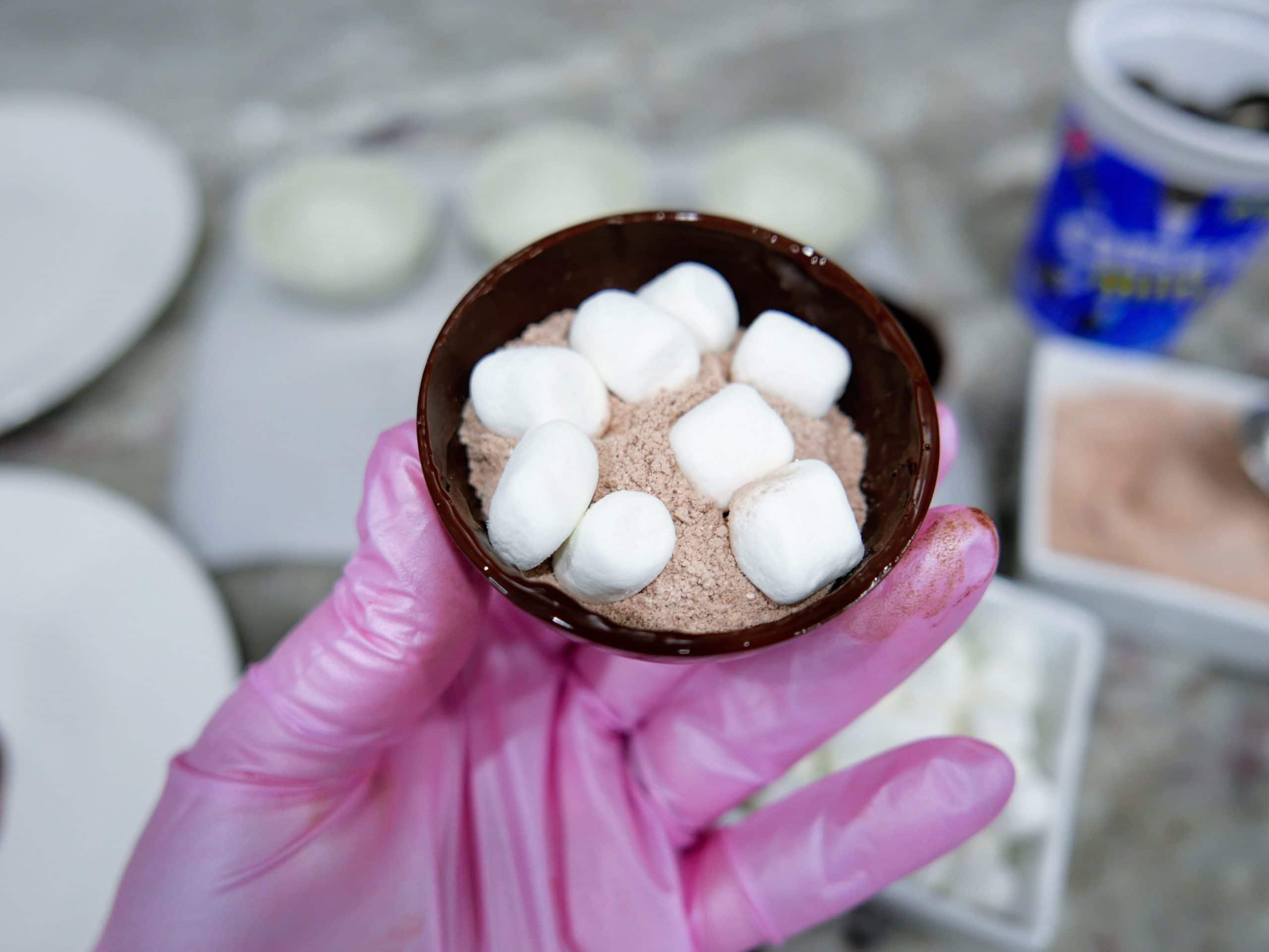 filling the inside chocolate shell with hot cocoa powder and marshmallows