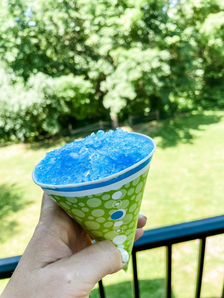 blue hawaiian shaved ice in a cone with trees in the background
