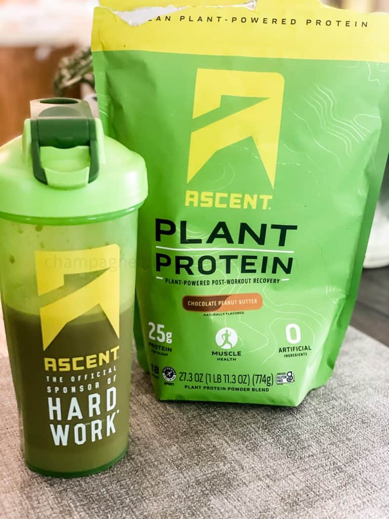 ascent protein powder bag behind a blender bottle