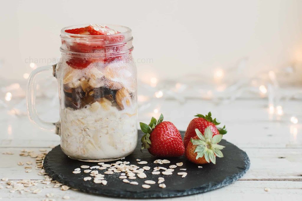 overnight oats on a black plate with a strawberry next to it