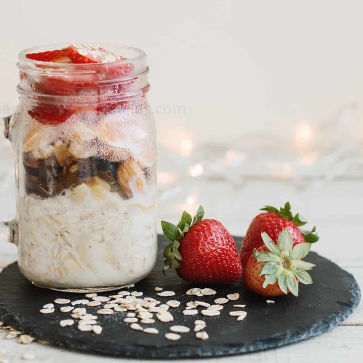 overnight oats on a black plate with a strawberry next to it