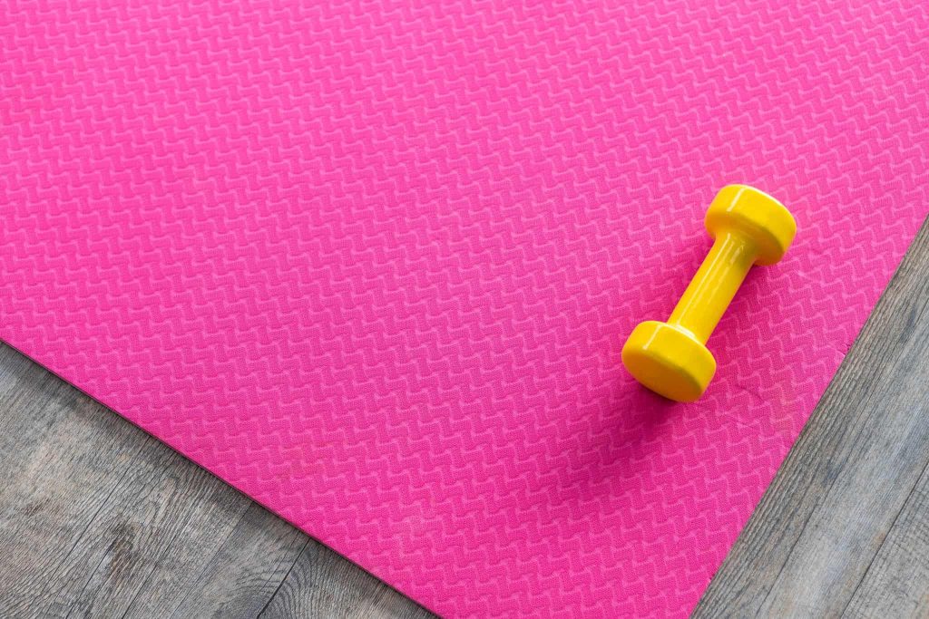 Dumbbells on an empty pink rubber floor on wooden floor background,top view with copy space health and exercise concept