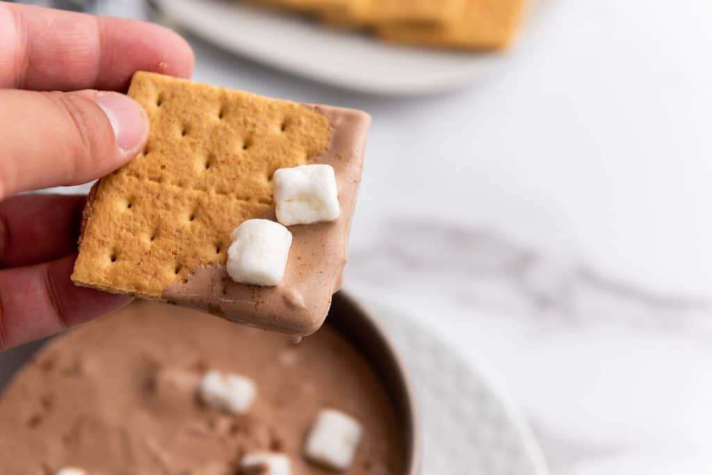 a graham cracker dipped in hot cocoa dip