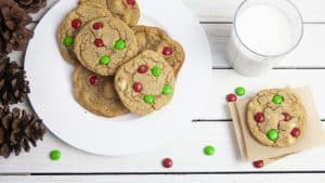 Christmas M&M cookies on a plate with a glass of milk