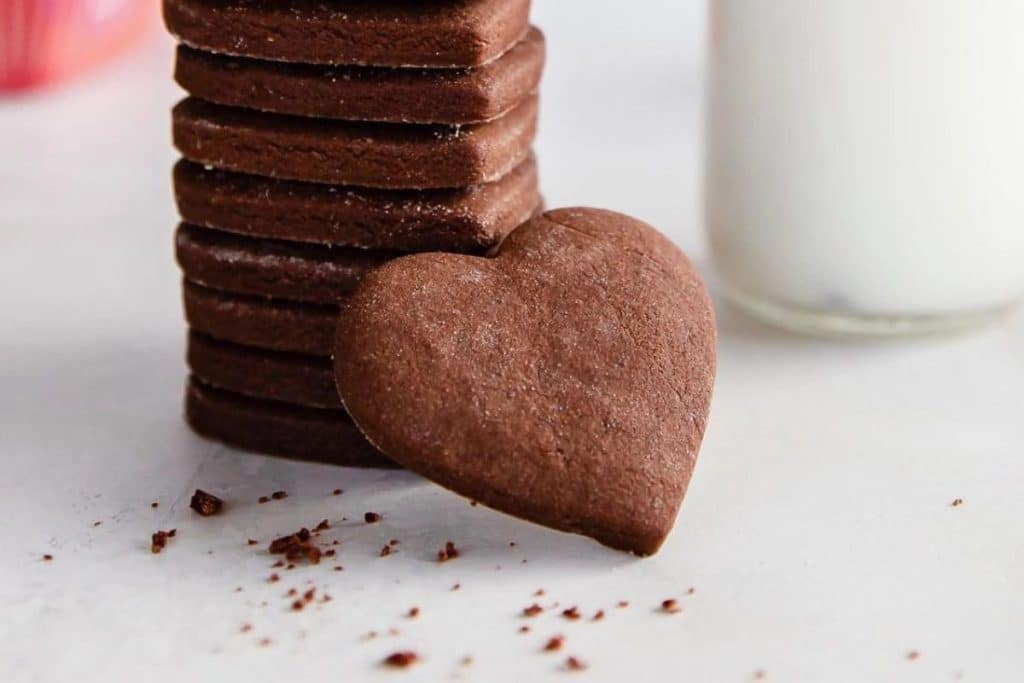 Stack of Chocolate cut out cookies with a heart shaped one leaned against the stack.