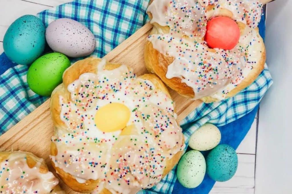 individual Easter bread rings covered in icing, sprinkles, and an easter egg nestled into the centers.